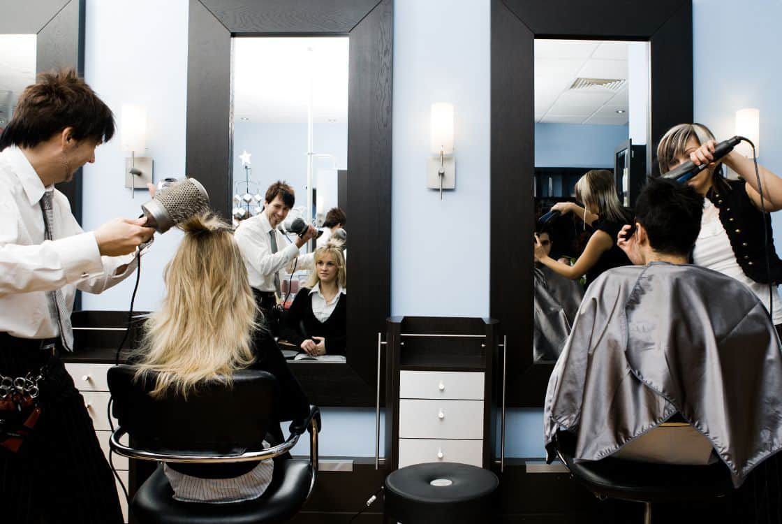Peluquero y peluquera trabajando en un salón de belleza