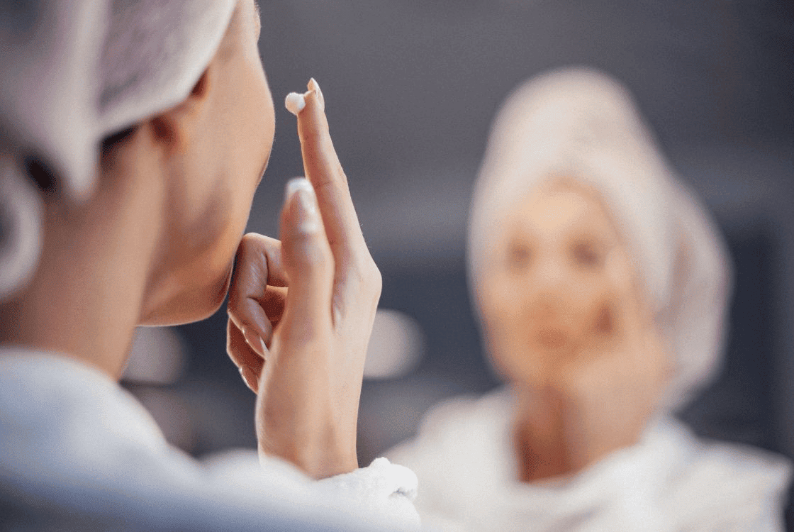 Mujer frente al espejo aplicando crema facial